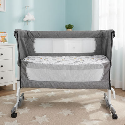 Lit pour bébé évolutif avec structure sécurisée, matelas intégré et côtés respirants, présenté vide sur fond neutre.