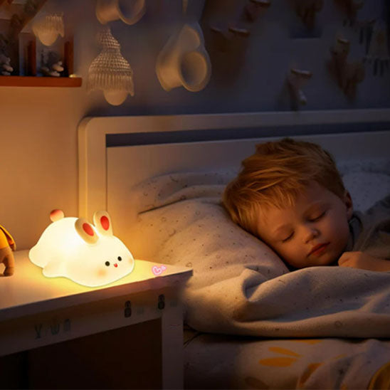 Veilleuse en silicone en forme de lapin mignon allumée sur une table de chevet-sphere de maman-nourrison