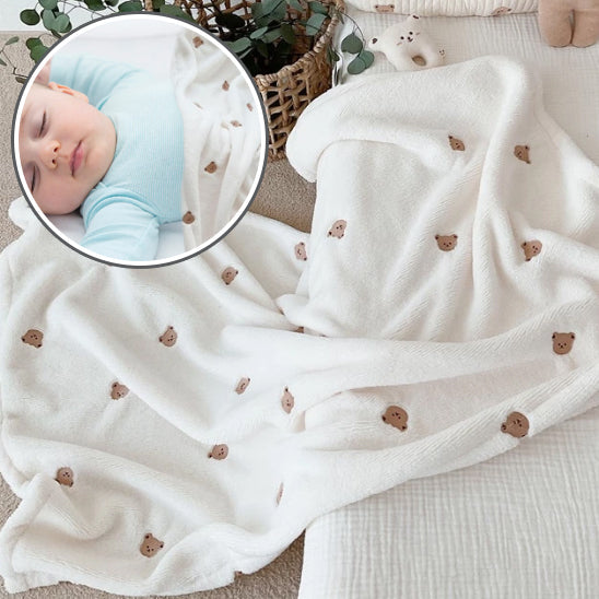 Couverture bébé douce en coton beige posée sur un lit-sphere de maman-nourrison