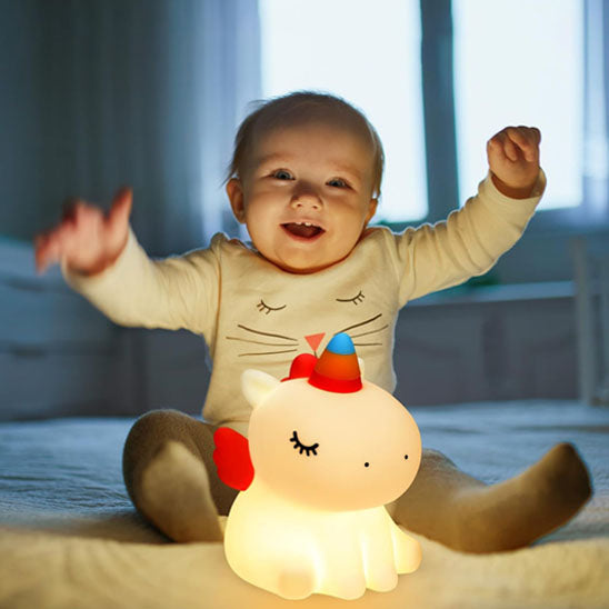 Enfant touchant une veilleuse en forme de licorne colorée-sphere de maman-nourrison