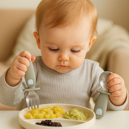 Bébé utilise la cuillère et la fourchette CuttieSpoon™ en silicone alimentaire, moment de repas en toute sécurité et autonomie.